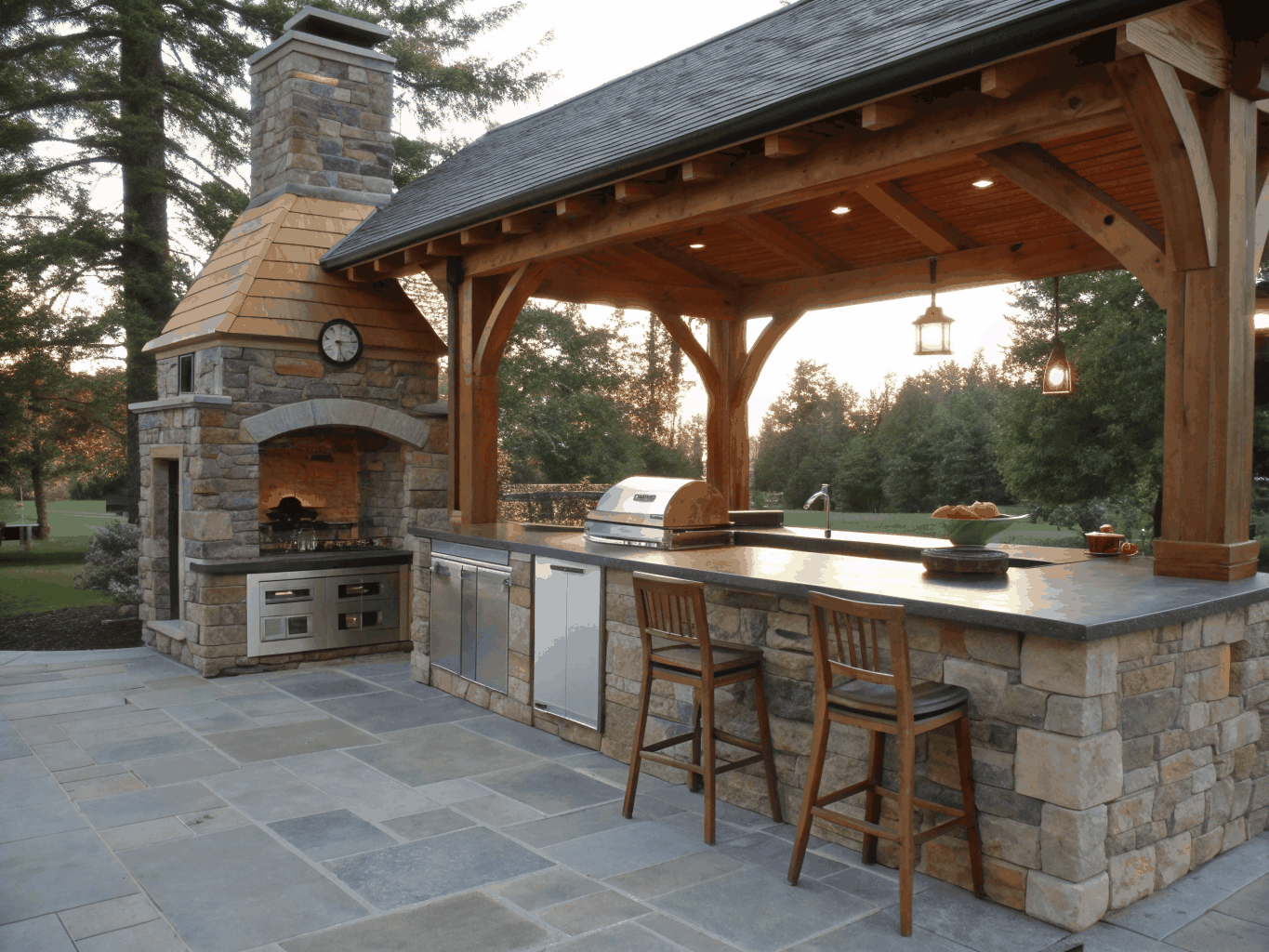 Custom outdoor living space with stone patio, covered pergola, and outdoor dining area
